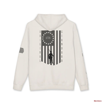 Back view of a Bone-colored hoodie featuring a large vertical American flag graphic. The flag's union contains a circle of 13 stars with "1776" in the center, and a silhouette of a colonial Minuteman is superimposed over the stripes. The words "ORIGINAL" and "STANDARD" run vertically down the left and right sides of the flag.