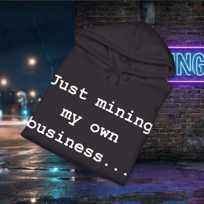 Black hoodie with text 'Just mining my own business...' against a nighttime city street background.