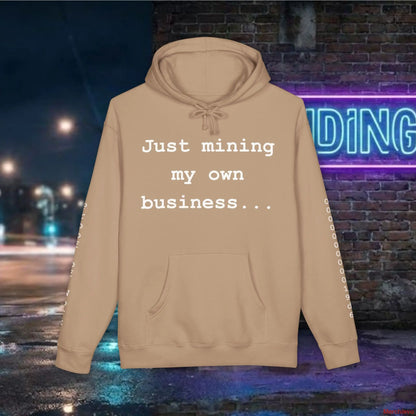 Beige hoodie with text 'Just mining my own business...' against a neon-lit street background