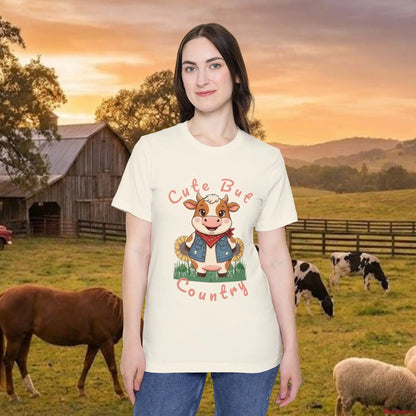 Woman modeling The Cute but Country Cow Tee in White. A premium 100% Airlume cotton t-shirt featuring a whimsical cow graphic with a floral crown and bandana, perfect for Southern style and farmhouse fashion.